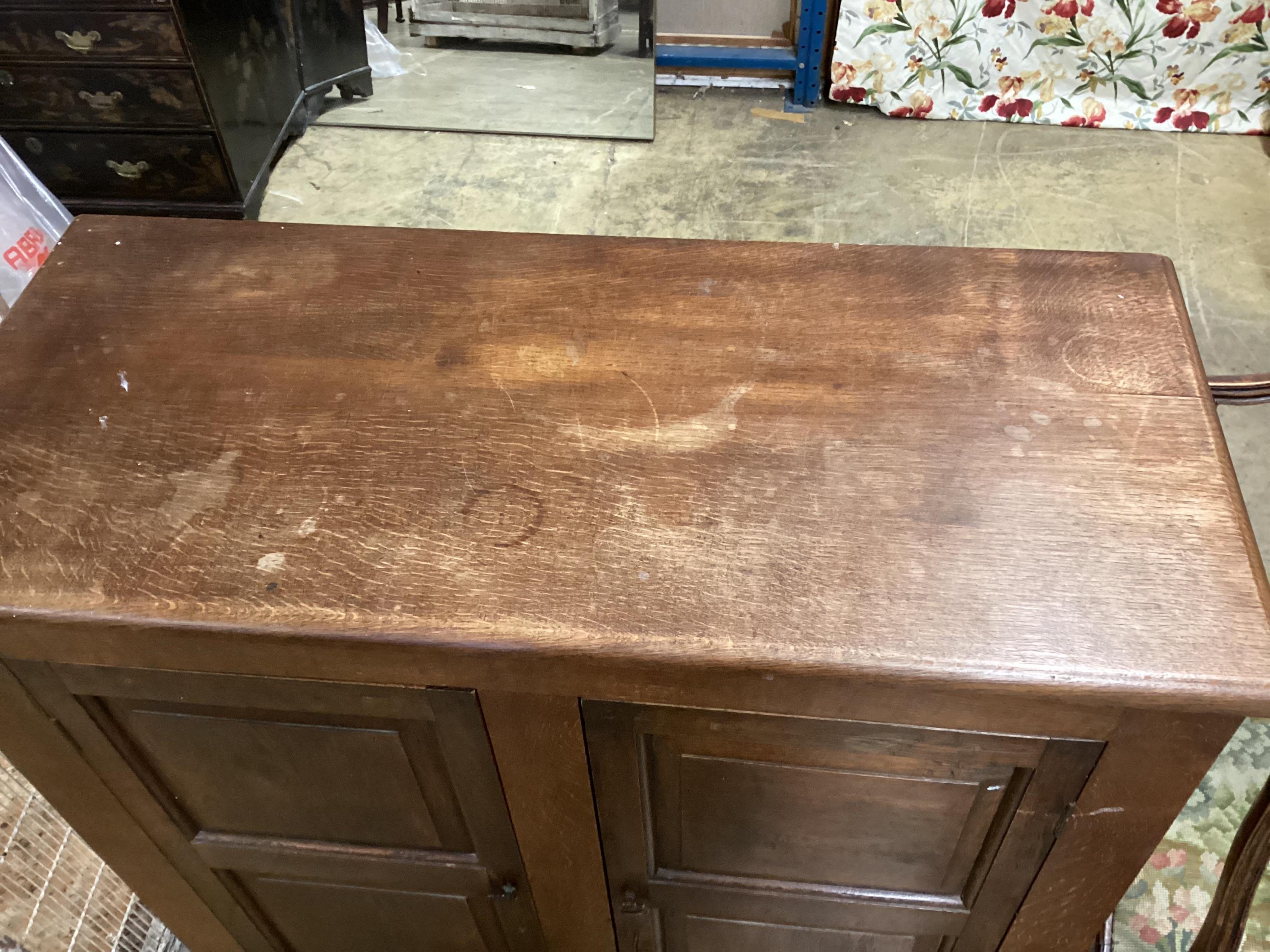 An early 20th century panelled oak two door cupboard, width 96cm, depth 42cm, height 112cm. Condition - fair, top faded, ring and spot stained.